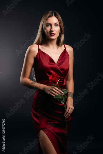 portrait of attractive awesome fair-haired woman in red dress holding a rose isolated on black studio. close up portrait, tenderness, love, romance, beauty , people