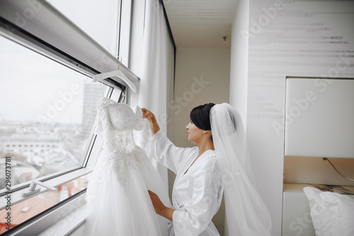 A elegant and beautiful bride at home standing near window