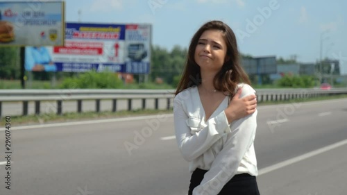beautiful young brunette woman trying to stop passing by cars on the road looks upset