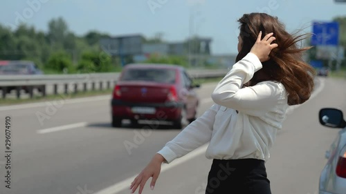 beautiful young sexy brunette woman trying to stop passing by cars on the road after having problems with her vehicle