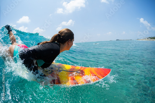 Young woman surfer takes off and starts riding the ocean tropical wave. The surf spot named Chickens in Maldives
