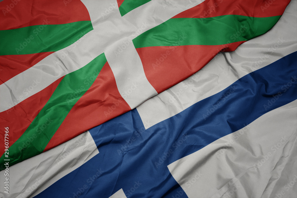 waving colorful flag of finland and national flag of basque country.