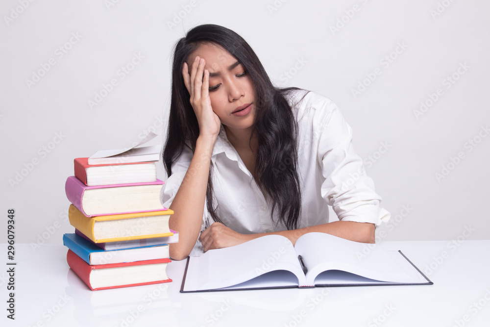 Exhausted Young Asian woman read a book with books on table. Exhausted Young Asian woman read a book with books on table.