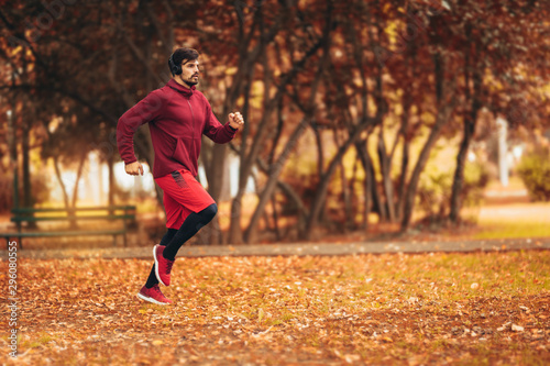 Young man running at park during autumn morning