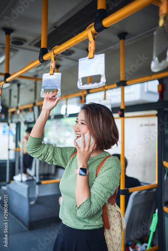 Beautiful young woman standing in city bus and talking on mobile phone.