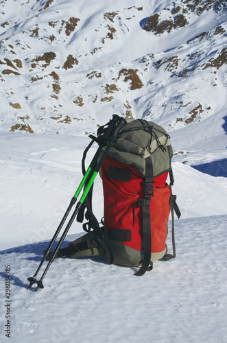Backpack and hiking poles on the snow. Abstract concept: winter sports, adventure, mountainering.