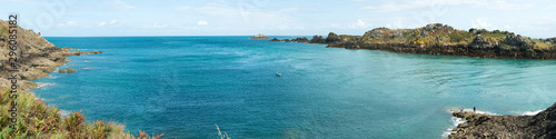 panorama view of rocky coast and ocean landscape with a lone fisherman in a small boat