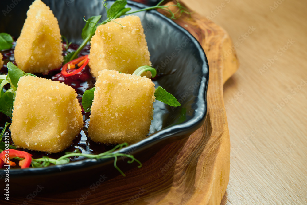 Deep fried crispy Camembert with cranberry sauce in a decorative pan on wooden background. Close up, selecive focus Deep fried crispy Camembert with cranberry sauce in a decorative pan on wooden background. Close up, selecive focus