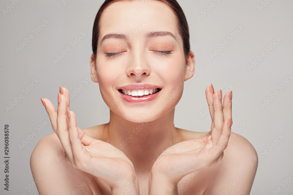 An elegant sophisticated beautiful girl with full lips, dark hair and radiant clean delicate skin on background. Happy lady holding her both hands near her face. Skin care, spa, beauty. An elegant sophisticated beautiful girl with full lips, dark hair and radiant clean delicate skin on background. Happy lady holding her both hands near her face. Skin care, spa, beauty.