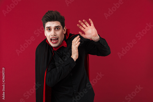 Image of displeased vampire man in black halloween costume being scared