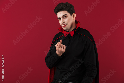 Fotografie Image of vampire man wit fangs in halloween costume calling with finger