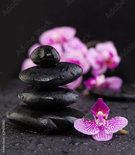 Asian zen stones with orchid flowers on black background with water drops