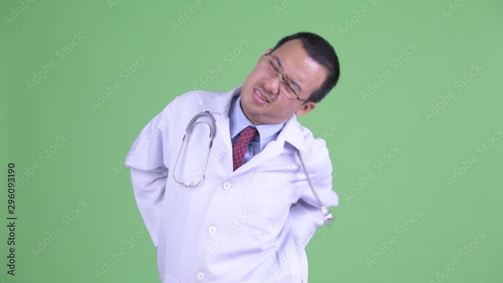 Stressed Asian man doctor with eyeglasses having back pain Stressed Asian man doctor with eyeglasses having back pain