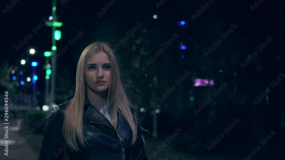 The girl walks alone in the evening park, against a background of colorful lanterns. The girl walks alone in the evening park, against a background of colorful lanterns.