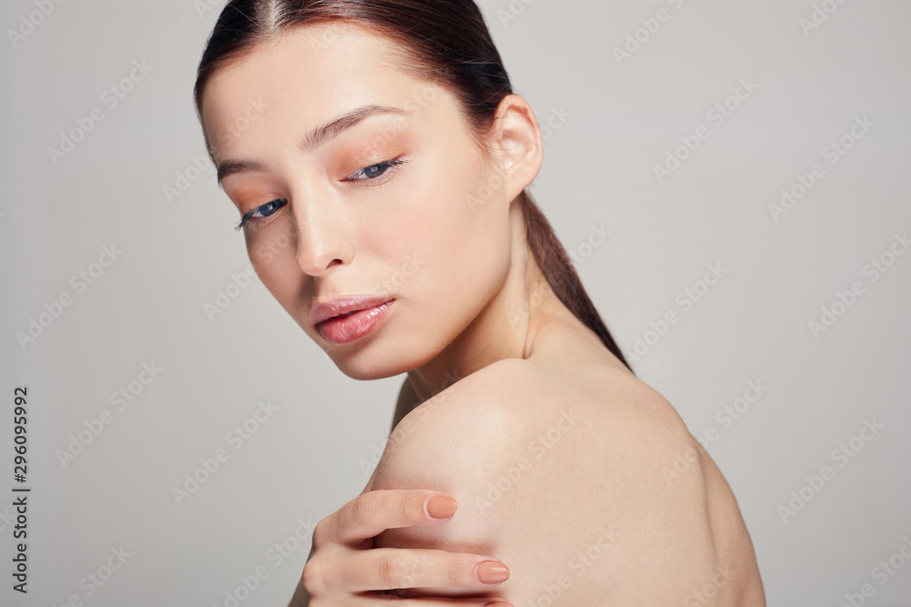 Young beautiful sophisticated girl with blue eyes and full lips holds a hand on his shoulder. background. Dark hair. Copy space. Close up. Young beautiful sophisticated girl with blue eyes and full lips holds a hand on his shoulder. background. Dark hair. Copy space. Close up.