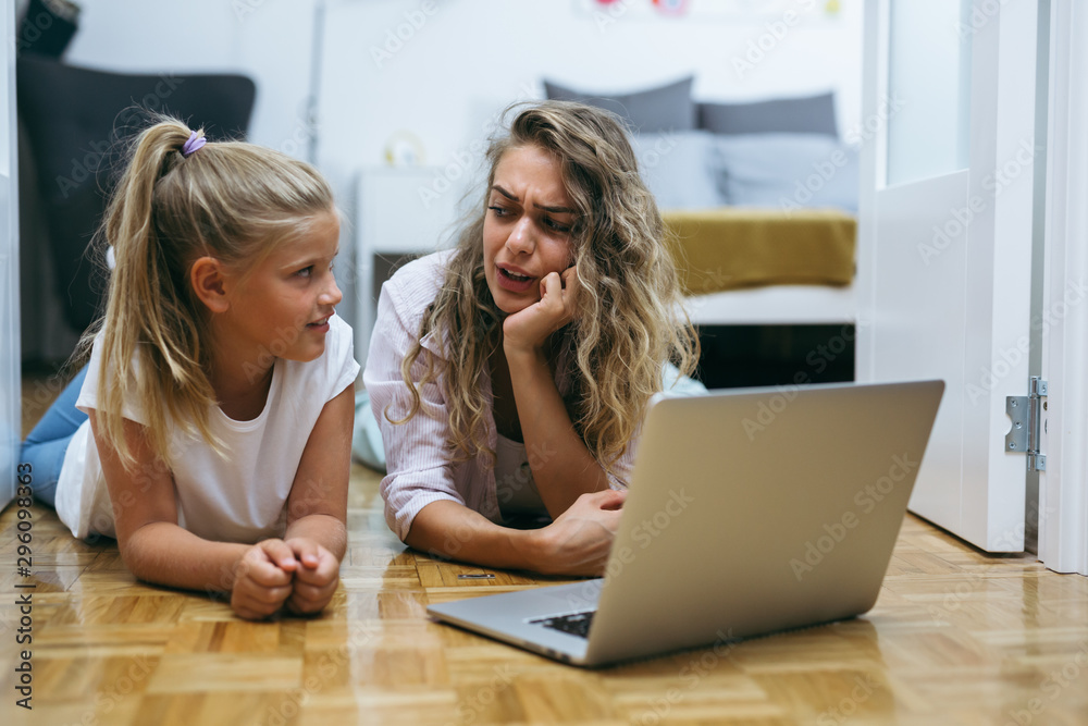 mother and daughter laying floor and using laptop computer at home