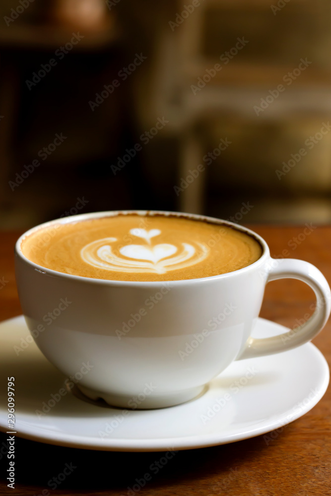 White cup of cappuccino with latte art on wooden background at coffee cafe. White cup of cappuccino with latte art on wooden background at coffee cafe.