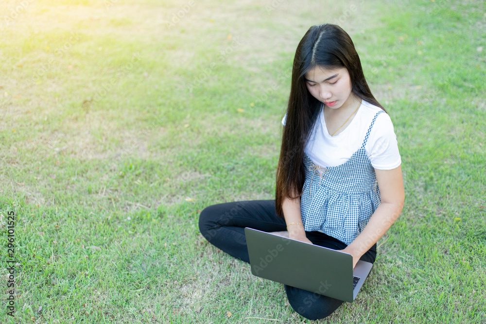 An Asian woman sat on the lawn and held with a smiling laptop face. An Asian woman sat on the lawn and held with a smiling laptop face.