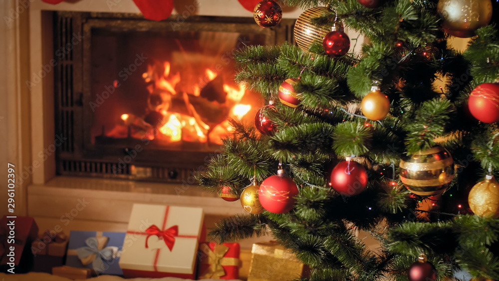 Closeup image of big stack of Christmas gifts and presents next to burning fireplace and decorated Xmas tree Closeup image of big stack of Christmas gifts and presents next to burning fireplace and decorated Xmas tree