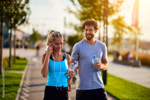 Modern woman and man jogging / exercising in urban surroundings and using cellphone at a pause / break.