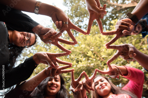 Group of hands showing peace hand sign, connecting fingers like star, down view
