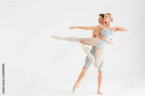 Young couple of modern ballet dancers posing over white studio background © benevolente