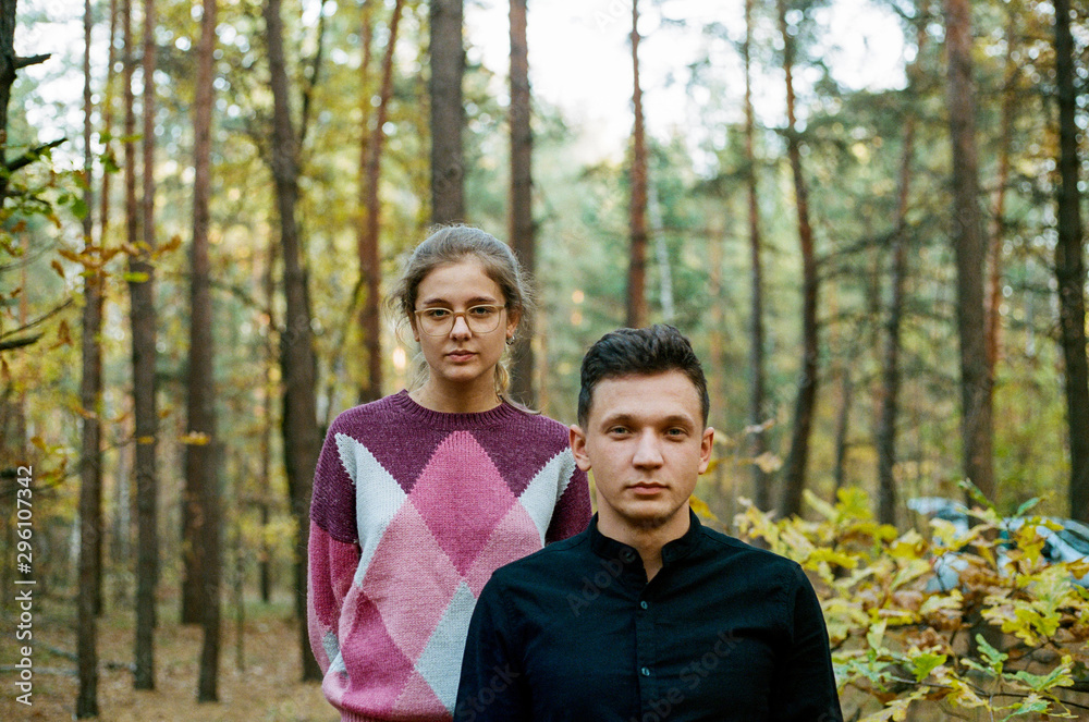 young girl and guy are standing in the autumn forest and looking directly at the camera young girl and guy are standing in the autumn forest and looking directly at the camera
