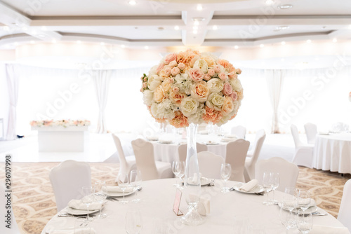 A large wedding bouquet of an assortment of fresh roses of pastel shades adorns the festive table