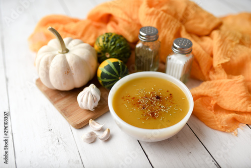 Pumpkin vegetable soup on white wooden backdrop and seasonings. Fall harvest soup 