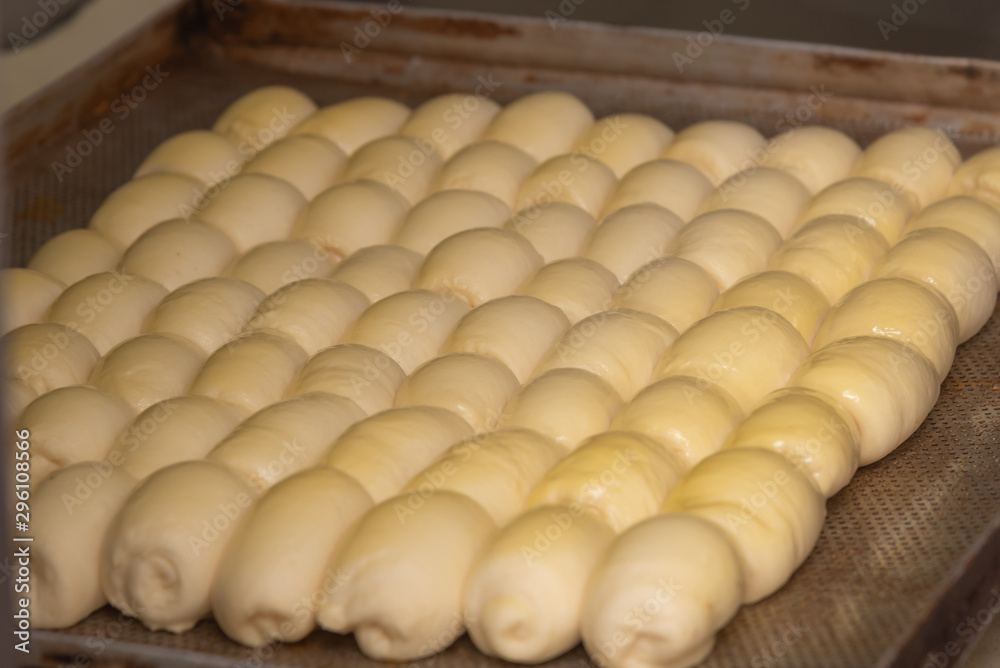 Fresh raw dough in product line. Cooks roll the dough for baking, pieces of raw dough on a metal board Fresh raw dough in product line. Cooks roll the dough for baking, pieces of raw dough on a metal board