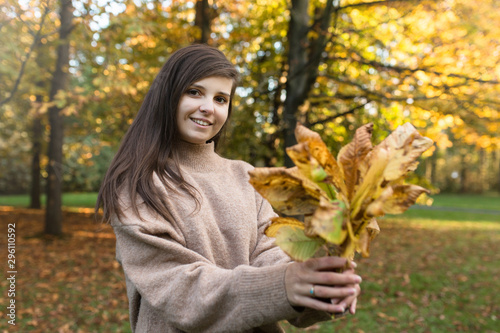 Uśmiechnięta dziewczyna trzyma liście w rękach.