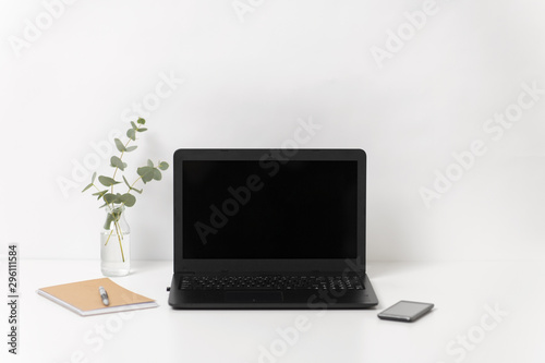 business, electronics and interior concept - laptop with black screen on white office table