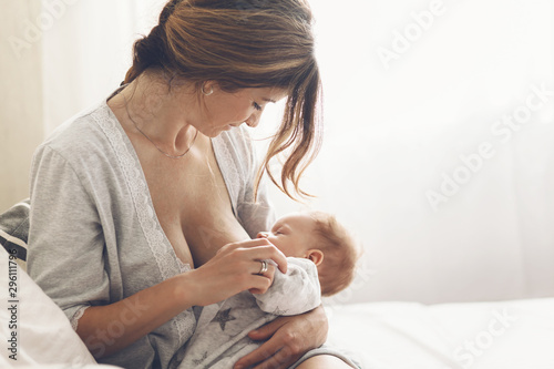 Loving mom breastfeeding her newborn baby at home photo