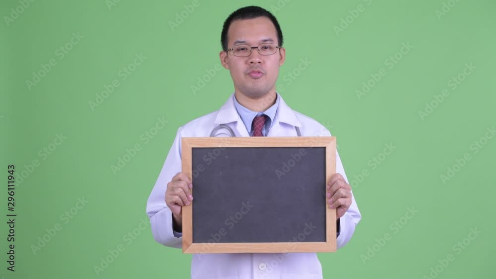 Happy Asian man doctor talking while holding blackboard Happy Asian man doctor talking while holding blackboard