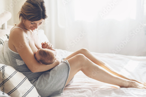 Billede på lærred Loving mom breastfeeding her newborn baby at home