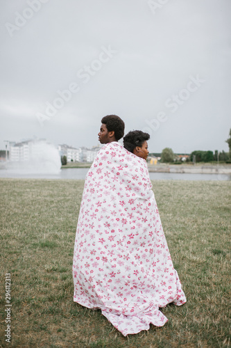 Loving couple covering theirselves by stylish sheet at nature. Strange people concept. photo