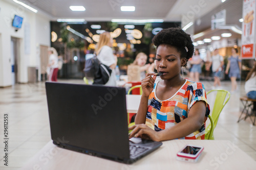 Beautiful Young Dark Skinned Freelancer Woman Using Laptop Computer Sitting At Cafe Table.  Freelance Work Concept. photo