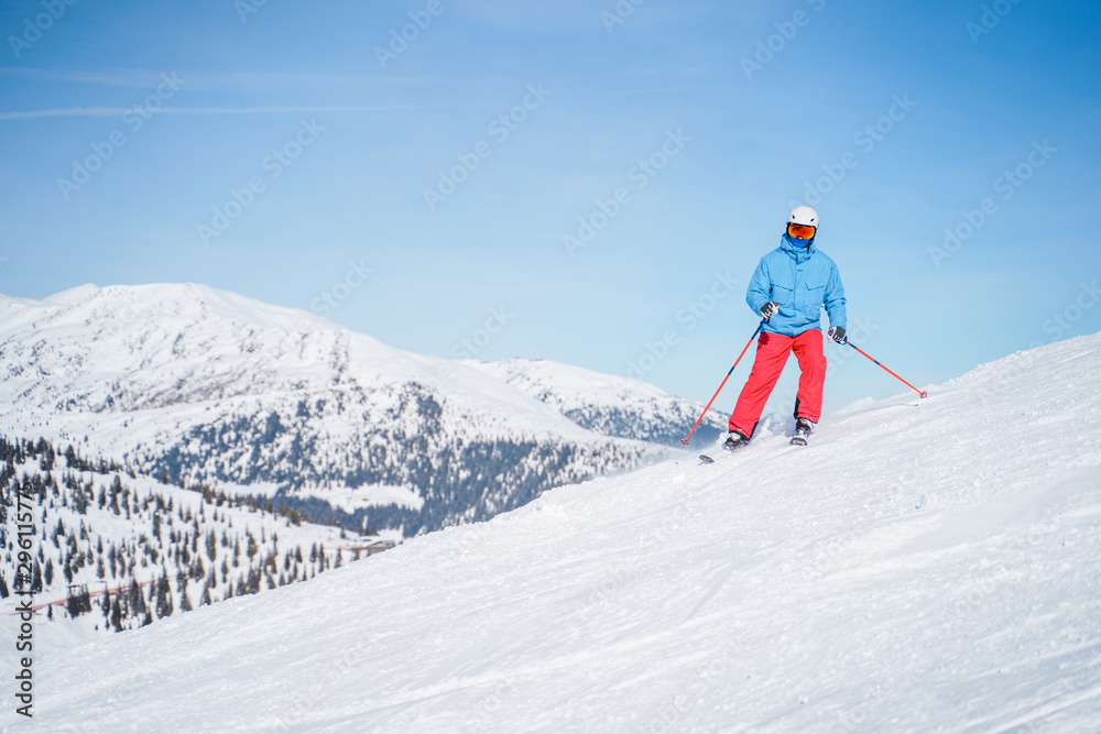 Athletic men in helmet skiing on snowy slope.
