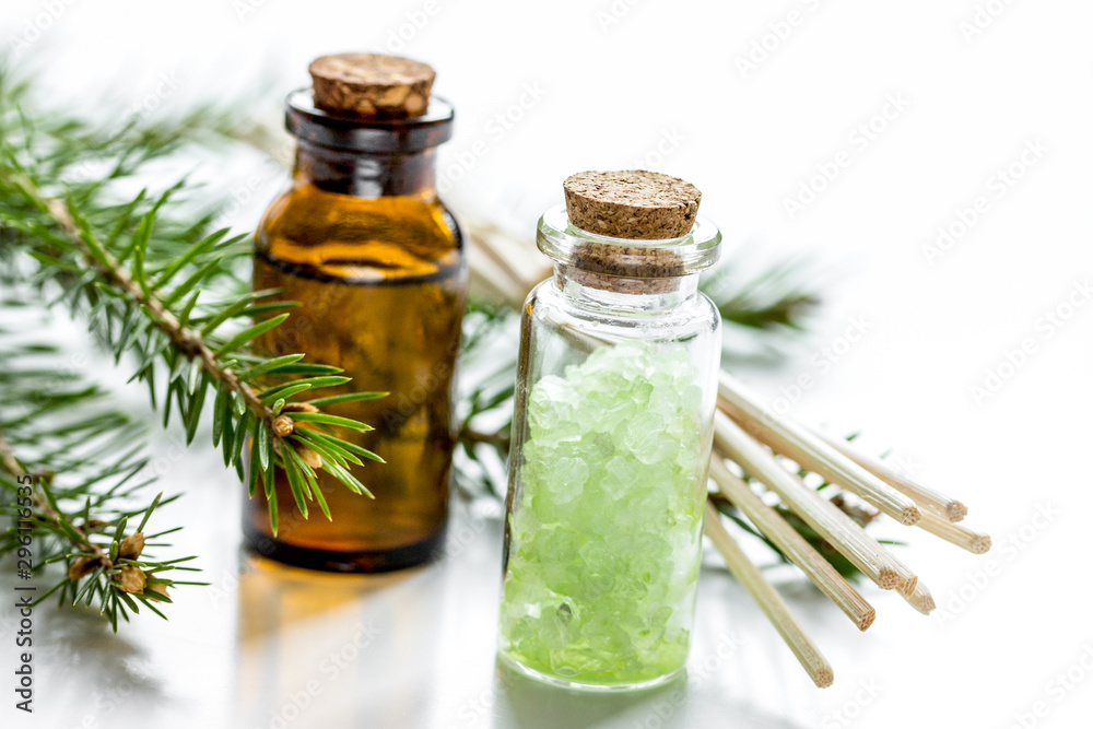 Spruce needle aromatherapy essential oils and salt in bottles on white table background Spruce needle aromatherapy essential oils and salt in bottles on white table background