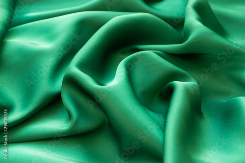 Smooth wavy elegant emerald green silk or satin luxury cloth texture background