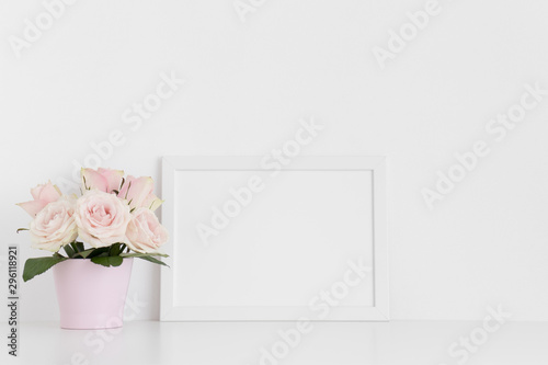 White frame mockup with pink roses in a pot on a white table.Landscape orientation.