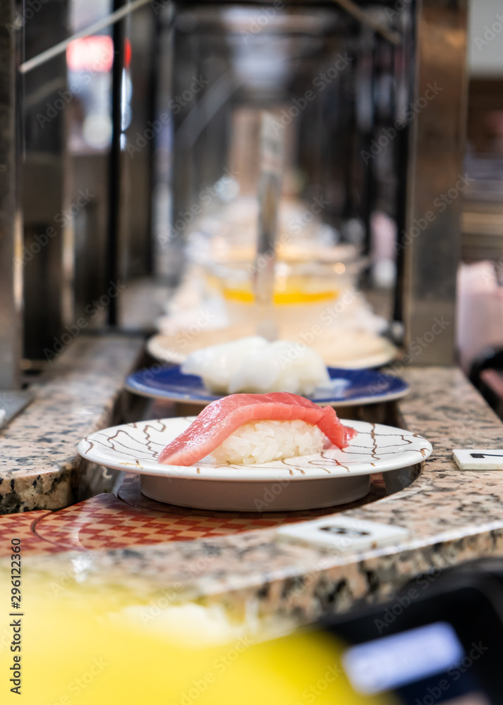 Fototapeta premium sushi that Japanese rice topping with sea fish placed in a white plate that placed on the belt