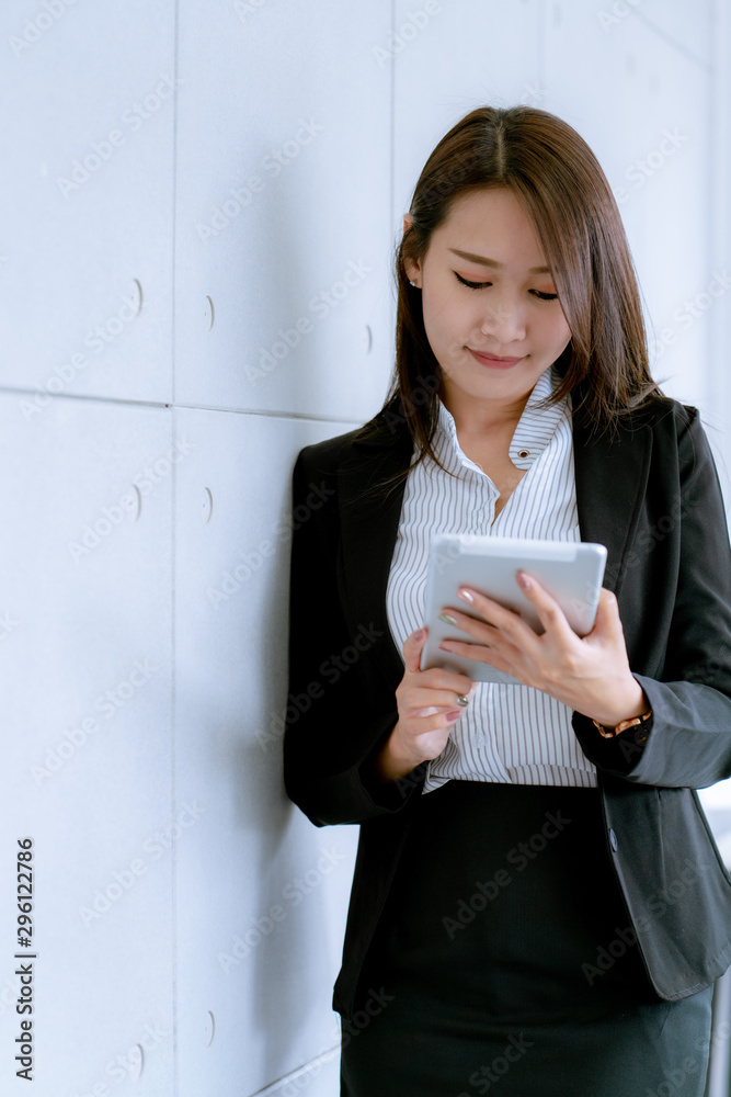 Asian beatiful young business woman in suit skirt using tablet to work about sales and marketing plan Asian beatiful young business woman in suit skirt using tablet to work about sales and marketing plan