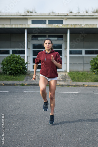 Female athlete running in place. Sporty young woman training on asphalt.