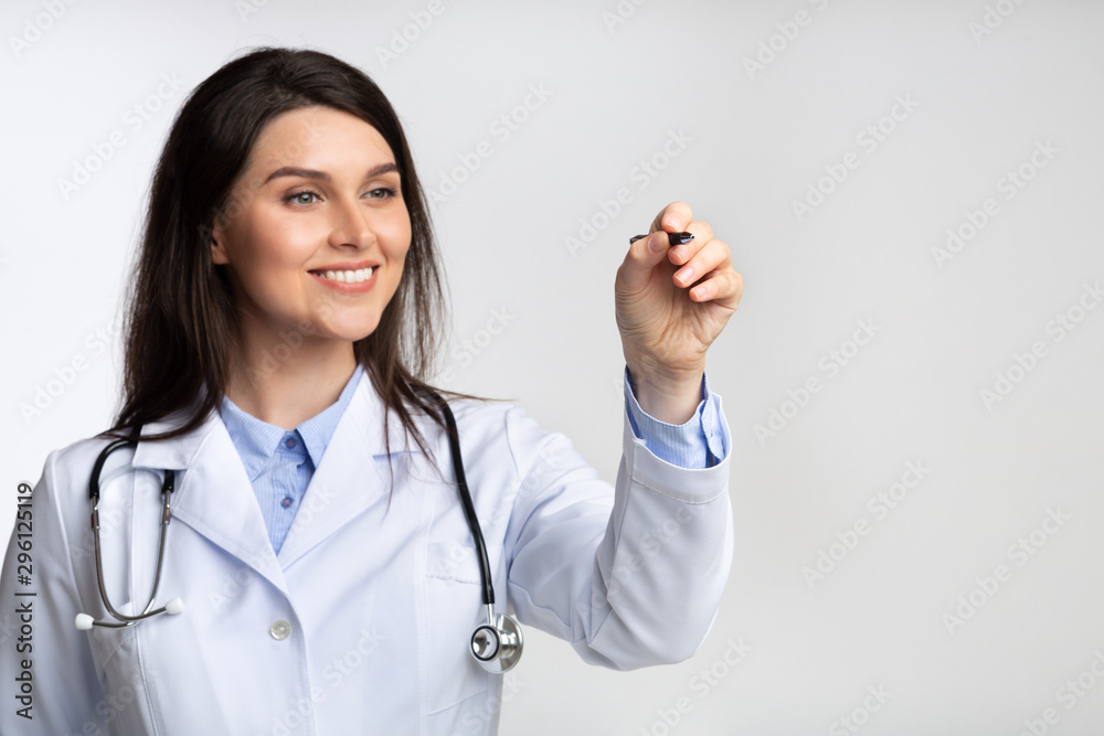 Female Doctor Using Stylus Drawing On Invisible Screen, Gray Background Female Doctor Using Stylus Drawing On Invisible Screen, Gray Background