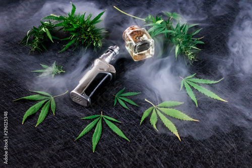 Cannabis liquid. Vape CBD or THC, Vaping Marijuana and Hemp. Against a Dark Background. Thick steam.