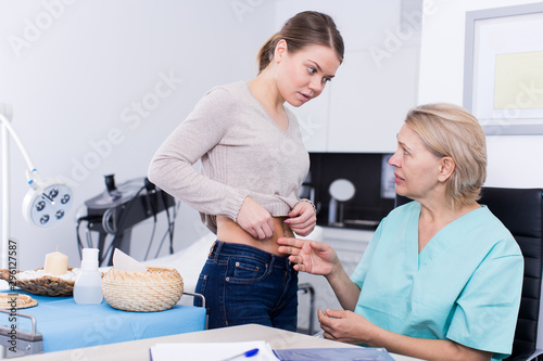 Cosmetologist examining girl body