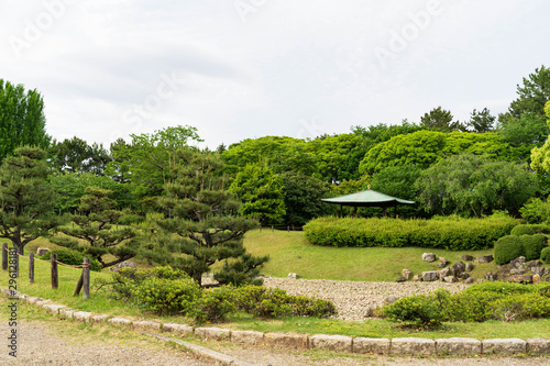 Japanese landscape beautiful public pine trees green garden,the traditional pavilion in the center of garden,green bushes surrounding of green grass and rocks of zen style on isolated sky in Japan.