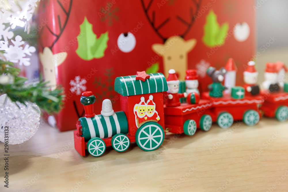 Christmas wooden train toys with snowman and friends and gift box in background.