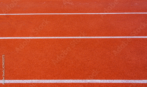 Red running track or resin Emboss Topping with white lines in outdoor sport stadium, side is a field and park. Backgrounds and rubber texture.